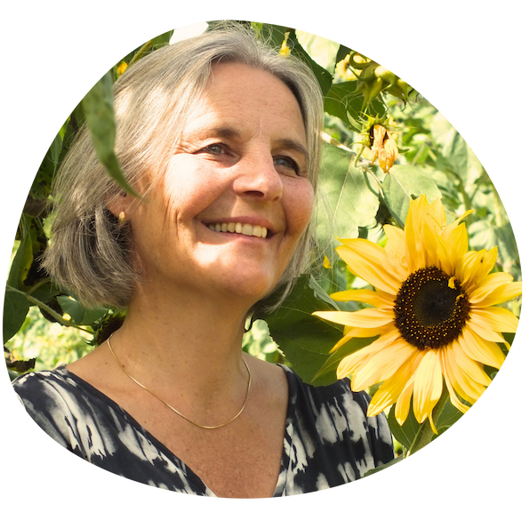 Energetikerin Christine Gningue blickt lächelnd zur Seite, neben einer großen Sonnenblume.