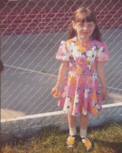 Ein Kindheitsfoto von Energetikerin Christine Gningue in einem bunten Blumenkleid.