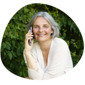 Energetikerin Christine Gningue lächelt beim Telefonieren mit dem Smartphone im Grünen.