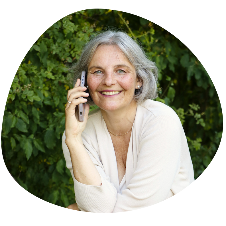 Energetikerin Christine Gningue lächelt beim Telefonieren mit dem Smartphone im Grünen.